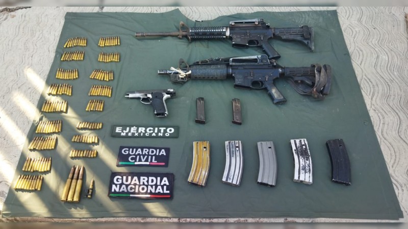 Policías y militares decomisando armas, cartuchos y cargadores; en Aguililla